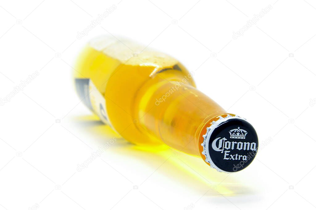 Lying on its side a bottle of light beer Corona Extra produced by Cerveceria Modelo in Mexico. Perspective view, cap close-up. Most popular imported beer. Selective focus. Moscow Russia - 11.19.2020