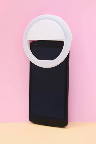 LED selfie dairesel ışık lambası. Pembe arka plandaki akıllı telefondan. Selfie çekmek için flaşlı kameralı telefon. Blogcular ve vloggerlar için kompakt aygıt. Dikey çekim