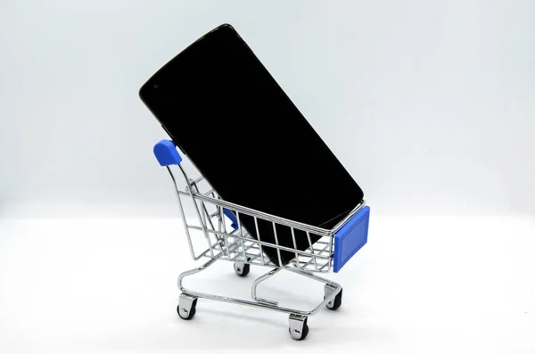 白い背景にスマートフォンと金属スーパーマーケットトロリー コンセプト オンラインショッピング オンライン注文の配信 スマートフォンを使用した商品の売買 スーパーマーケットアプリケーション — ストック写真