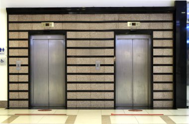 İki asansör kapısı. İş merkezindeki ya da apartmandaki asansör platformu. Engelli tekerlekli sandalye kullanıcıları için işaret levhası kaldırma. Kavram: kamusal alanlarda erişilebilir ortam.