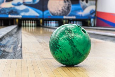 Yeşil bovling topunu bowling salonundaki boş şeritlerin arka planına yakın çekim yap. Aktif boş zaman. Tüm aile için spor aktiviteleri. Metin için boşluk.