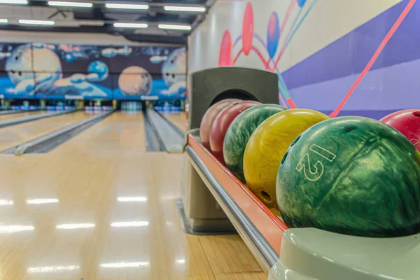 Bowling balls against background of empty lanes in bowling alley. Active leisure. Sports activities for whole family. Space for text. Selective soft focus, blurred background