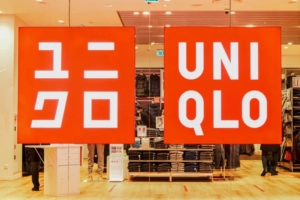 Alışveriş merkezindeki cam vitrinde UNIQLO giyim mağazasının logosu ve markası ile parlayan tabela. UNIQLO, Japon holding şirketi FAST 'ın sekiz markasından en büyüğü. Moskova Rusya 01.10.2021
