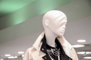 Kadın giyim mağazasının satış alanında zarif ceketli bir kadın mankeni. Vitrindeki kadın bebek. Alışveriş, güzellik veya kadınsı konsept.