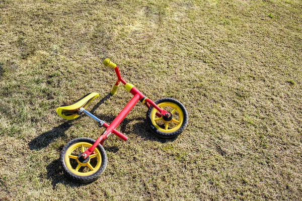 Rowerek Biegowy Dla Dzieci Czerwoną Ramą Leży Wiosennym Trawniku Parku — Zdjęcie stockowe