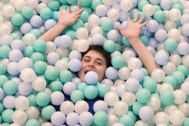 Genç esmer kadın plastik toplarla havuzda eğleniyor. Çocuk oyun oynarken, çocukların eğlence merkezindeki anne seviniyor. Seçici odak.