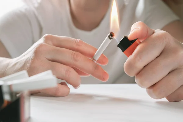 Close-up of hands lighting a cigarette with a lighter. The concept of combating smoking, bad habits.