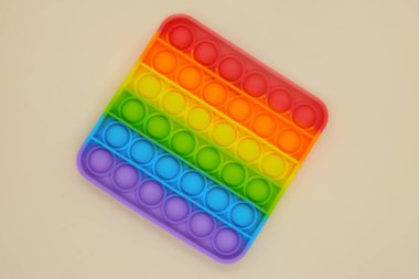 Gökkuşağı Meydanı Fidget Oyuncakları açık bej arka planda. Pop Bubble 'ı it. Popüler gevşetici kare şekilli silikon stres atma oyuncağı. Üst görünüm
