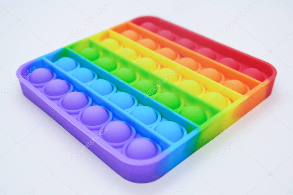 Rainbow Square Fidget Toys Pop-it on the light background. Push Pop Bubble. Popular Relaxing square shape silicone stress relief toy. View from an angle in perspective.