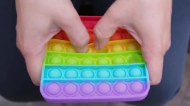 Kadın elleri gökkuşağı Meydanı Oyuncak Toy-it 'i tutuyor. Renkli silikon anti-stres oyuncağı patlat. Popüler gevşetici kare şekilli silikon stres giderici oyuncak kullanarak.
