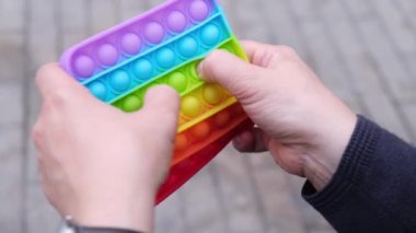 Kadın elleri gökkuşağı Meydanı Oyuncak Toy-it 'i tutuyor. Renkli silikon anti-stres oyuncağı patlat. Popüler gevşetici kare şekilli silikon stres giderici oyuncak kullanarak.