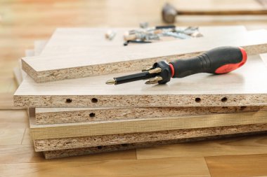Kabine mobilyalarının kaplamalı çip arka planında mobilya montajı için çıkarılabilir başlıklı tornavida. Kabine mobilyalarının kendiliğinden montajı.