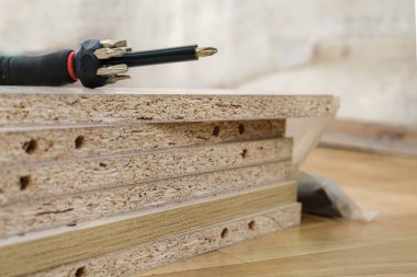 Kabine mobilyalarının kaplamalı çip arka planında mobilya montajı için çıkarılabilir başlıklı tornavida. Dolap mobilyalarının kendiliğinden montajı. Seçici odak