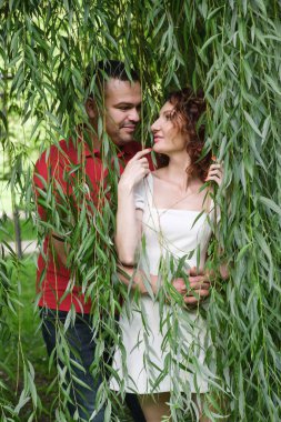 Söğüt dallarında birbirine aşık bir çiftin portresi ve birbirlerine şefkatle bakmaları. Kırmızı tişörtlü, kıvırcık saçlı karısıyla Orta Doğulu bir adam. Mutlu karı koca parkta yürüyorlar..