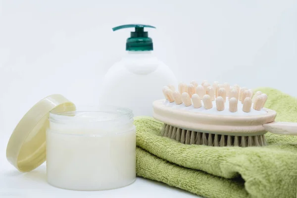 Vücut fırçalamak için çift taraflı masaj fırçası beyaz arka planda yeşil bambu havluya uzanır. Dispenser kremi ve anti-selülit vücut fırçası kavanozu. Spa tedavileri için malzemeler