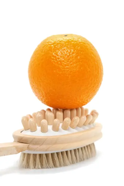 白い背景に体のための両面手動マッサージブラシのオレンジ 肌を象徴するオレンジピールラフ 抗セルライト創造的な概念 — ストック写真