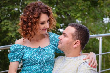 Parkta birbirini seven bir çift birbirlerine şefkatle bakar. Tişörtlü bir adam ve randevuda giyinmiş kıvırcık bir kadın. Kadın, kocasının kucağında oturuyor. Aile yaz yürüyüşü.