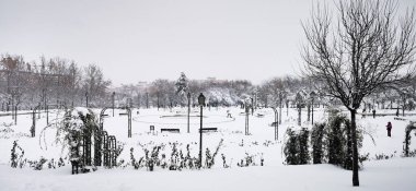 Madrid, Spain- January 9, 2021: Parks of Madrid frozen by snow, Storm Filomena. Great snowfall in Madrid. Snow covered cars. clipart