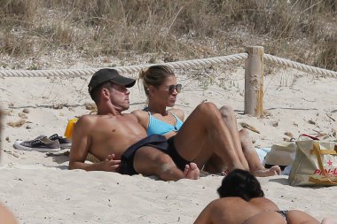 Formentera, Spain- August 12, 2019: Diego Pablo Simeone and his wife Carla Pereira lying on the sand. Holidays in Formentera. Cholo Simeone and Carla on vacation in the Mediterranean