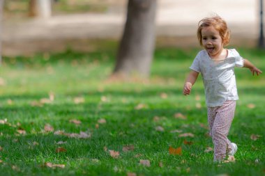 Parktaki çimlerde koşan ve oynayan küçük bir kız. Çocuklar...