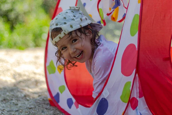一个戴着帽子和奶嘴的小女孩在布屋里玩耍 — 图库照片
