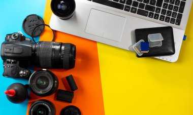 Birçok fotoğraf aksesuarının yanındaki dizüstü bilgisayarın üst görüntüsü. Bir kamera, lensler, filtreler, piller, hafıza kartları, sabit disk ve lensleri temizlemek için bir üfleyici.