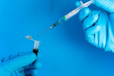 Bir insan şırıngayla, bir kan örneğiyle mikro santrifüj tüpüne bir çeşit reaktör karıştırır. Kopyalama alanı olan mavi arkaplan.