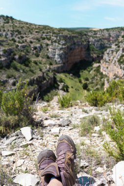 Derin bir dağ kanyonunun kenarında bağdaş kurmuş güzel mavi bir gökyüzü olan biri..