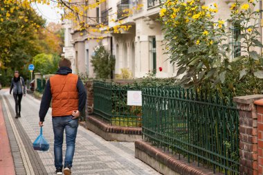 Çek Cumhuriyeti 'nde kış başlarken COVID-19 salgını nedeniyle Prag 7' de tek başına yürüyen adam karantina döneminde alışveriş torbalarını taşıyor.