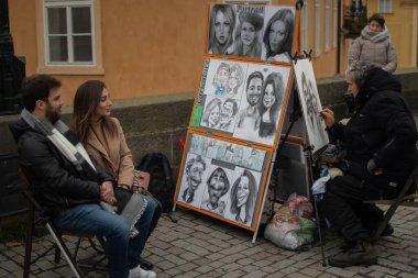 Prag, Çek Cumhuriyeti. 01-11-2020. Turistler Prag 'ın tarihi kasabasındaki Charles Köprüsü' nde yürüyorlar. Prag 'daki Charles Köprüsü' nde bir sanatçı bir çift çiziyor..