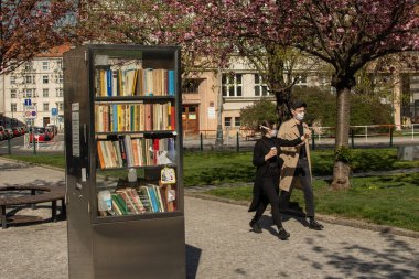 Prag, Çek Cumhuriyeti. 03-08-2020. Arkadaşlar kaldırımda yürüyor, dışarıda kütüphane var. Prag 'da, karantinaya rağmen insanlar iyi vakit geçirmek, egzersiz yapmak, yürümek, koşmak, bisiklete binmek için dışarı çıkarlar..