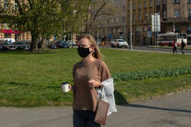 Prag, Çek Cumhuriyeti. 03-08-2020. Bir fincan kahveyle yürüyen bir kadın. Prag 'da, karantinaya rağmen insanlar iyi vakit geçirmek, egzersiz yapmak, yürümek, koşmak, bisiklete binmek için dışarı çıkarlar..