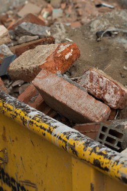 Yıkım tuğlaları konteynırda. Çöplerle dolu bir konteynır. İnşaat alanı. Bina yeniden inşa ediliyor. Tuğla, orman, metal, toz gibi çöpler.