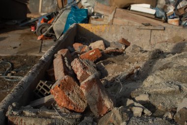 Çöplerle dolu bir konteynır. İnşaat alanı. Bina yeniden inşa ediliyor. Tuğla, orman, metal, toz gibi çöpler.