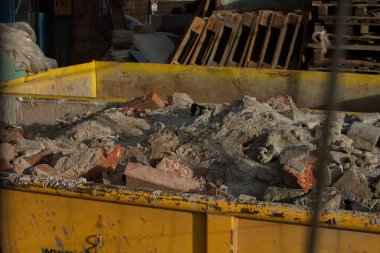 Yıkım tuğlaları konteynırda. Çöplerle dolu bir konteynır. İnşaat alanı. Bina yeniden inşa ediliyor. Tuğla, orman, metal, toz gibi çöpler.