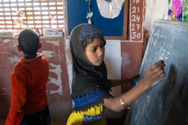 Rajasthan. Hindistan. 07-02-2018. Okulda okurken tahtaya yazı yazan güzel kız, Hindistan 'da fakir bir mahallede yaşıyor..
