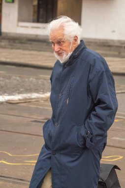 Prag, Çek Cumhuriyeti. 01-29-2021. Prag 'ın merkezinde güneşli ve soğuk bir kış sabahı valiz taşıyan yaşlı bir adamın portresi..