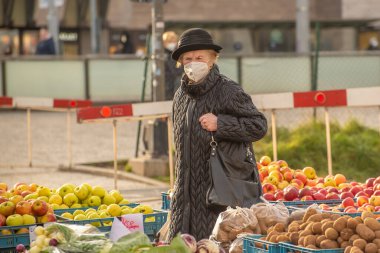 Prag, Çek Cumhuriyeti. 01-29-2021. Prag 'ın merkezinde, güneşli ve soğuk bir kış sabahı meyve ve sebze pazarındaki yaşlı bir kadının portresi..