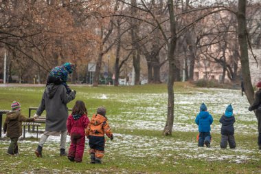 Prag, Çek Cumhuriyeti. 01-31-2021. Prag 'da soğuk kış günlerinde kar üzerinde yürüyen öğretmen ve küçük çocuklar Letna