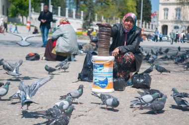 İstanbul, Türkiye. 05-23-2018. Türkiye 'de İstanbul sokaklarında güvercinlere mısır satmak için çalışan Müslüman yaşlı kadın.