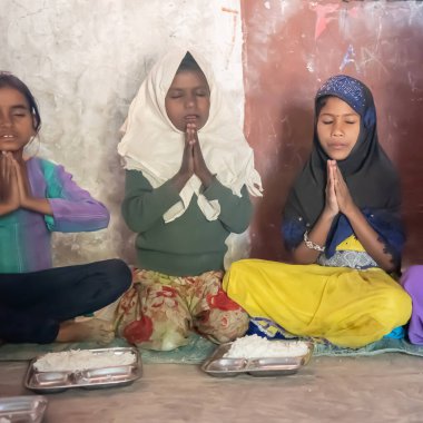 Rajasthan. Hindistan. 05-02-2018. Üç genç kız öğle yemeği yemeden önce dua ediyor..