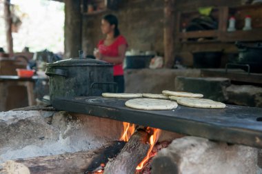 Suchitoto, El Salvador. 06-25-2016. Annem onların yaşadığı evde yemek pişiriyor. Ülkenin kırsal kesimlerinde yaşayan insanlar, sığır yetiştirmeye ve hayatta kalmak için sebze yetiştirmeye bel bağlıyorlar..