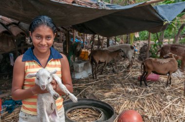 Suchitoto, El Salvador. 06-25-2016. Kırsal kesimde yaşadıkları evde keçi yavrusu tutan bir kız. Ebeveynlerine günlük görevlerinde yardım ediyor..