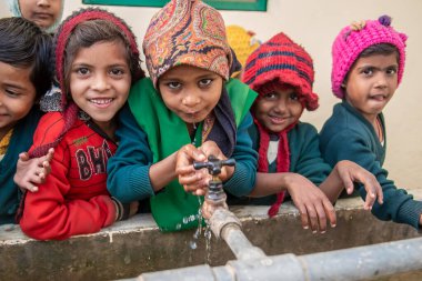 Uttar Pradesh. 05-15-2018. Kızlar okulda su içiyor. Çocukların ailelerini geçindirmek için çalışmak zorunda olan pek çok çocuk için kaliteli eğitim alma olanağı vardır..