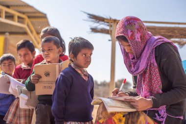 Uttar Pradesh. 05-15-2018. Öğretmen okulda bir öğrenci ödevini düzeltiyor. Çocukların ailelerini geçindirmek için çalışmak zorunda olan pek çok çocuk için kaliteli eğitim alma olanağı vardır.