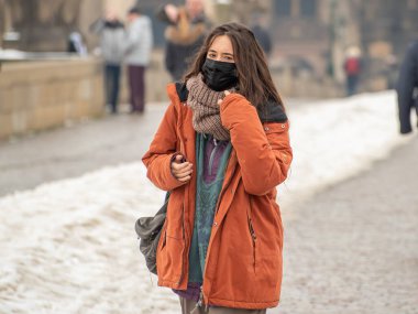 Prag, Çek Cumhuriyeti. 02-23-2021. Prag şehir merkezinde, Charles Köprüsü 'nde yürüyüp, kış boyunca soğuk bir günün tadını çıkaran zarif ve şık bir turist kadın.