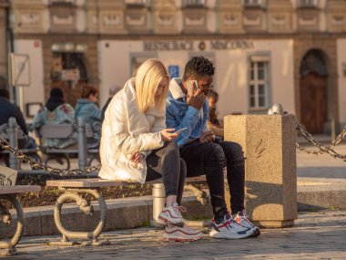 Prag, Çek Cumhuriyeti. 02-24-2021. Soğuk bir kış günü Prag şehir merkezinde genç bir beyaz kadın ve siyah bir adam telefonuyla konuşuyor..