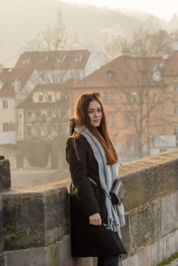 Prag, Çek Cumhuriyeti. 03-02-2021. Güzel, çekici ve şık bir genç kadın Prag 'ın şehir merkezindeki Charles Köprüsü' nde güzel bir gün batımıyla birlikte..