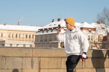 Prag, Çek Cumhuriyeti. 02-23-2021. Prag 'ın şehir merkezinde Charles Köprüsü' nde telefonla koşan genç sporcu kış boyunca soğuk bir günün tadını çıkarıyor.