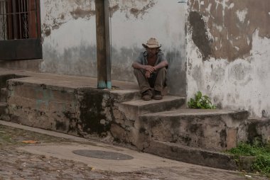 Suchitoto, El Salvador. 03-18-2019. Suchitoto 'da uzun bir çalışma gününden sonra yaşlı işçi kaldırımda oturuyor..